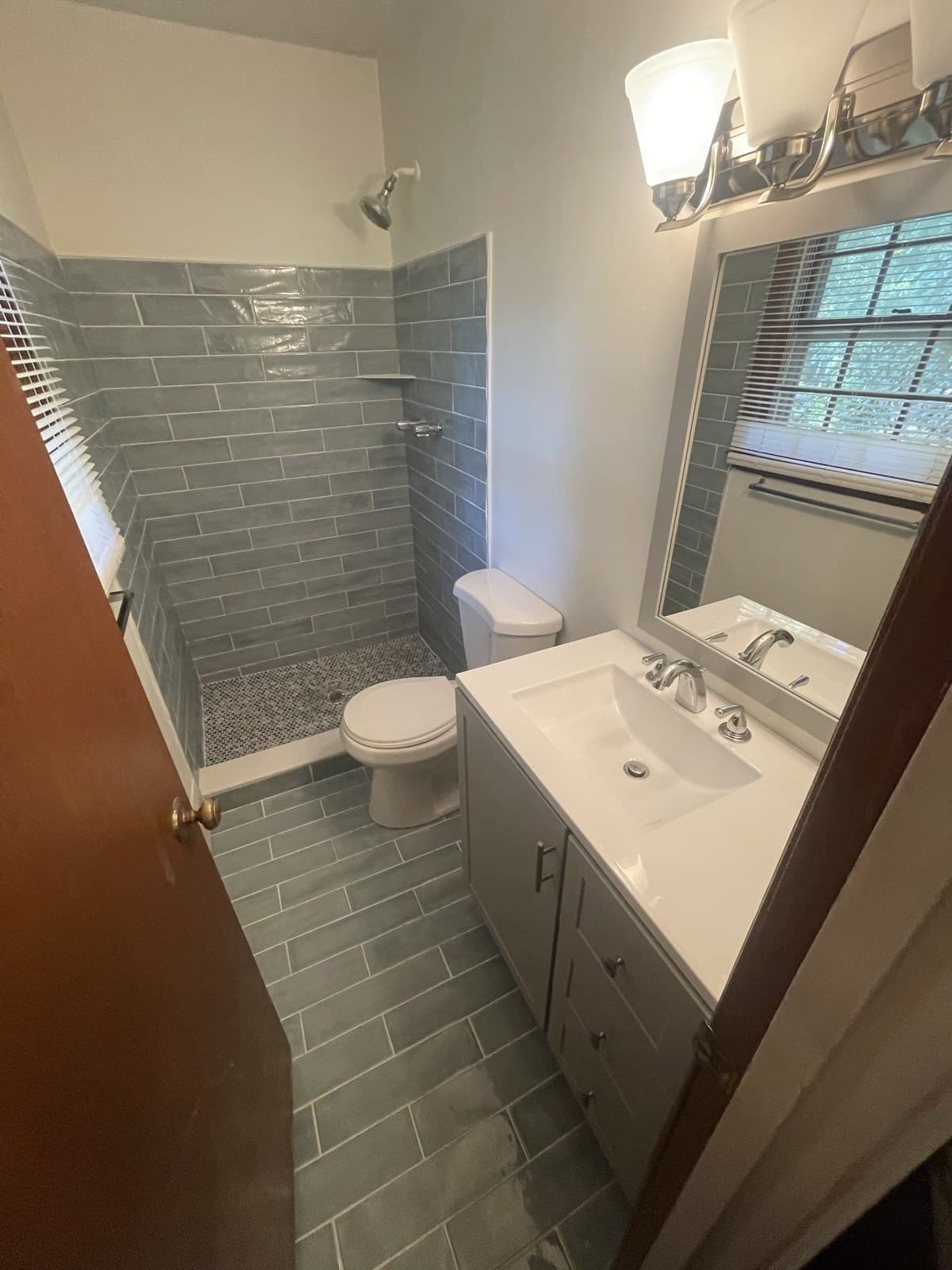 Completed bathroom remodel with subway-tile shower, tile floor, and new vanity