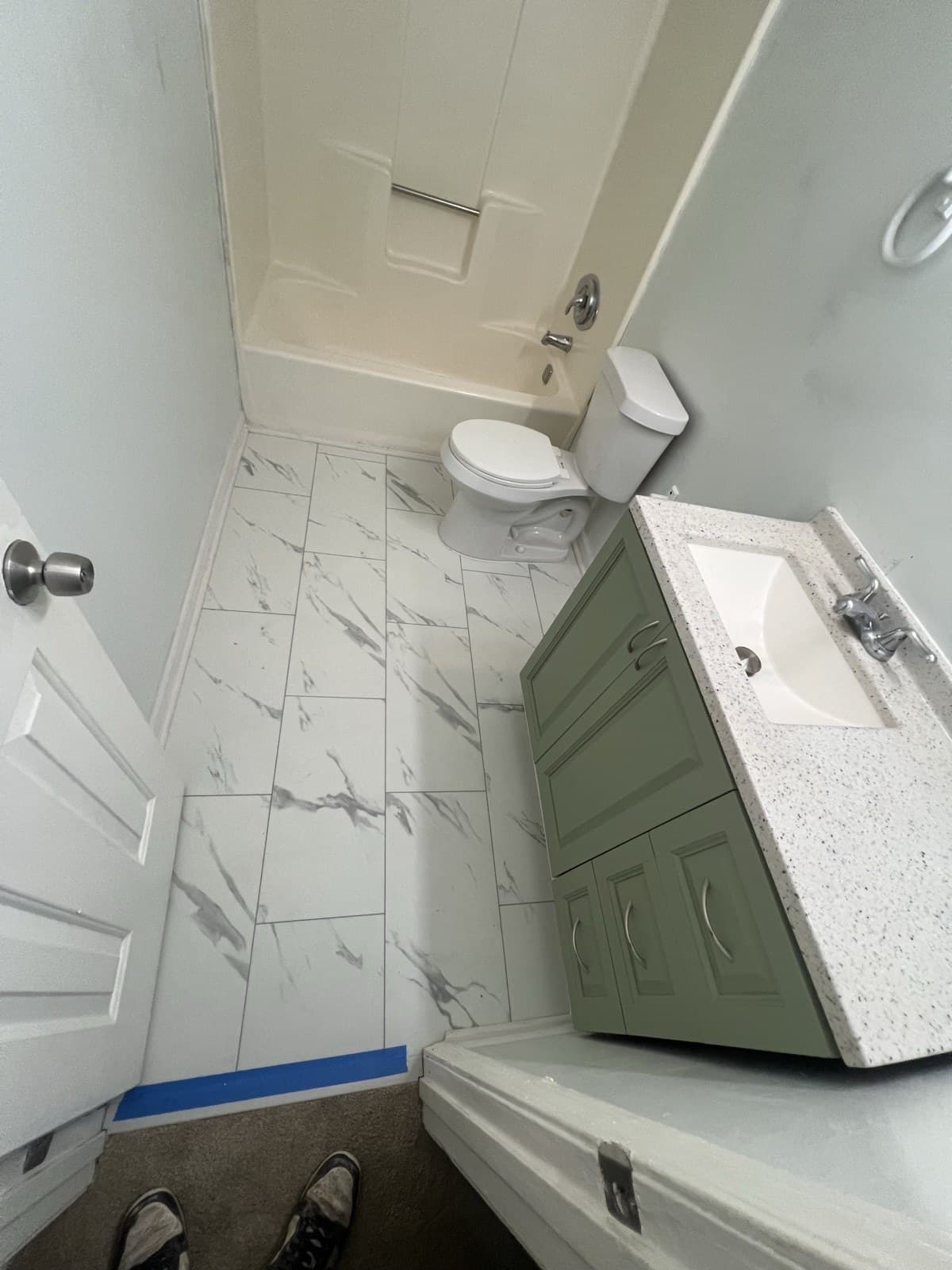 Remodeled bathroom with marble-look tile floor and new vanity