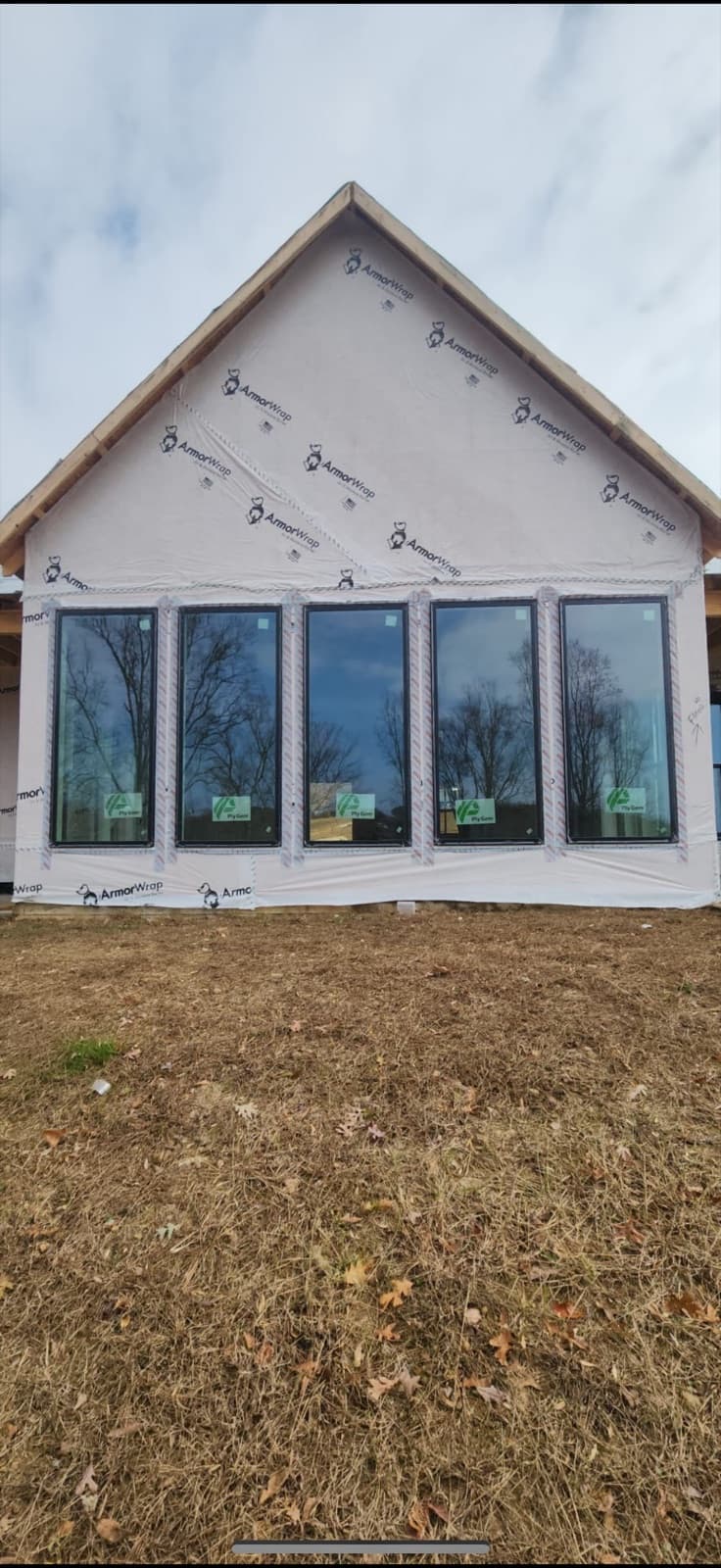Five tall black-framed windows installed in a new-construction gable